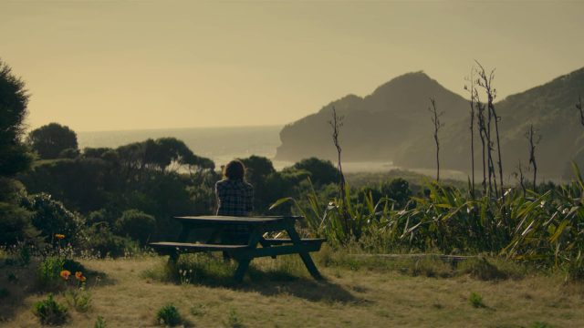 Girl sat on a bench over looking the coast